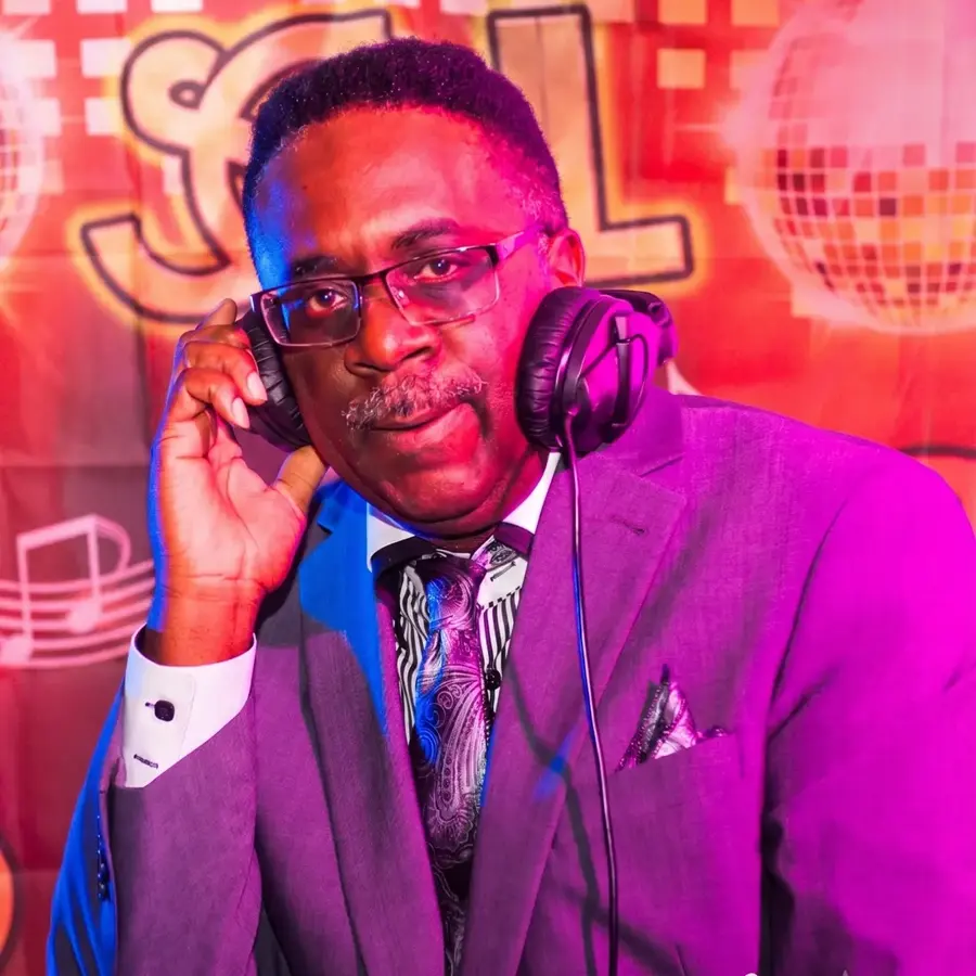 DJ Roy Stone in a purple suit with headphones at a Soul Train themed event